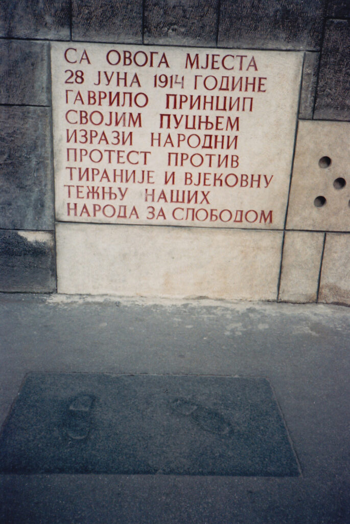 Мемориальная доска на месте убийства, прославляющая Принципа, «выразившего своим выстрелом народный протест против тирании и вековую борьбу наших народов за свободу» (фото сделано в 1987 году; в 1992 году надпись заменен